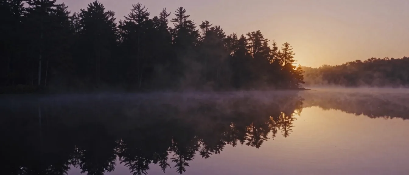 A still North Carolina mountain lake mirroring the dawn sky