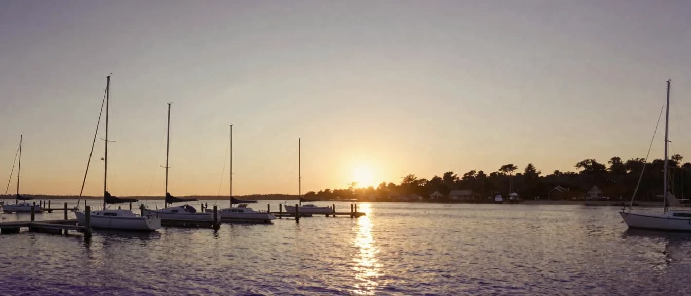 Sailboats moored at a coastal marina at golden hour